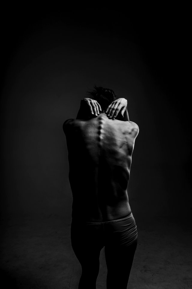 grayscale photograph of person reaching to its back