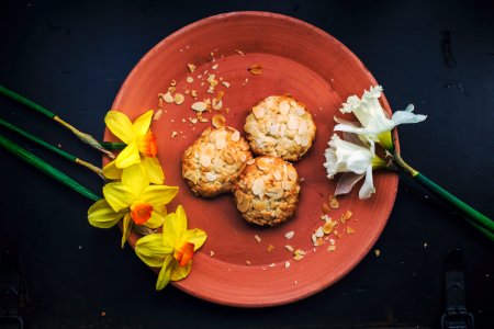 three round cookies on brown plate with petaled flowers photo