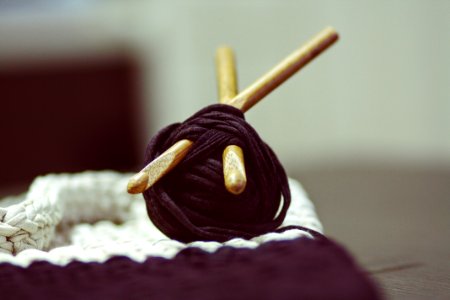 brown yarn roll with two brown crochet hooks on top of white surface photo