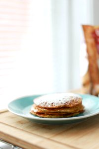 selective focus photography of four piece pancakes with powdered sugar on top in blue ceramic plate