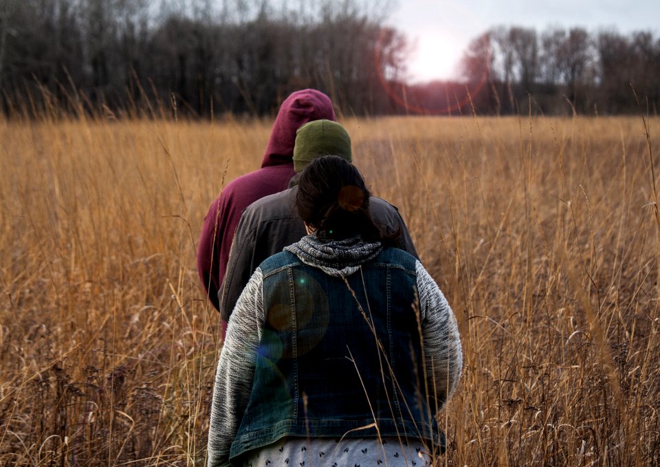 three person walking on brown field during daytime