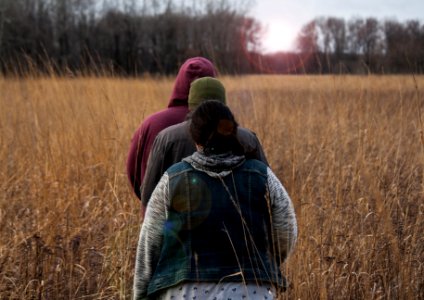 three person walking on brown field during daytime