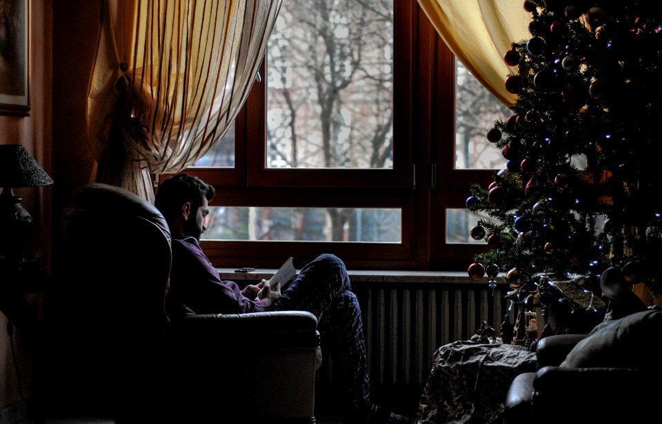 man sitting on sofa chair near Christmas tree