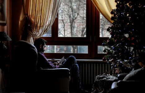 man sitting on sofa chair near Christmas tree
