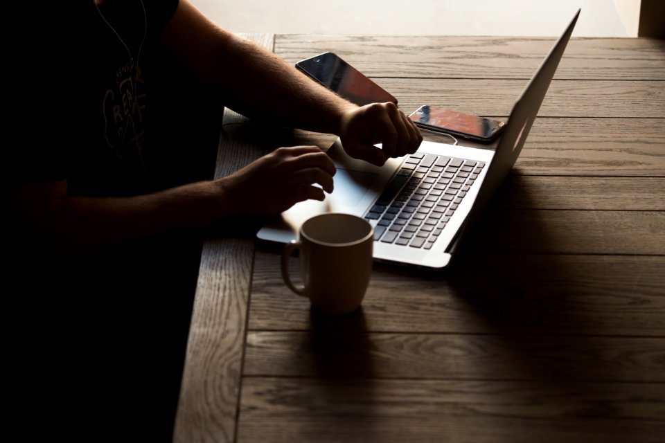 gray laptop computer on brown wooden table beside person sitting on chair photo