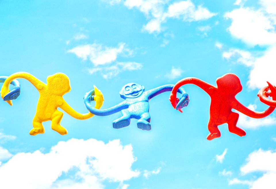 three assorted-color monkey plastic toys holding each other during daytime
