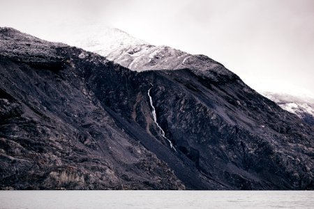 grayscale photo of body of water surrounded by mountain