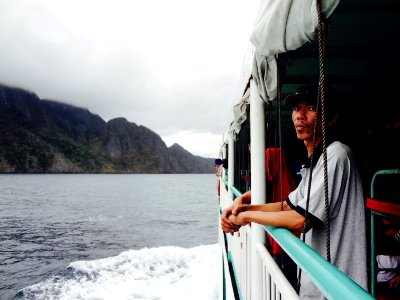 man wearing gray polo shirt standing beside boat on sea