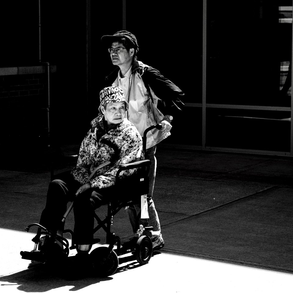 gray scale photo of man pushing wheelchair