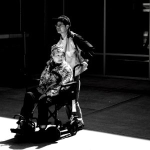 gray scale photo of man pushing wheelchair photo