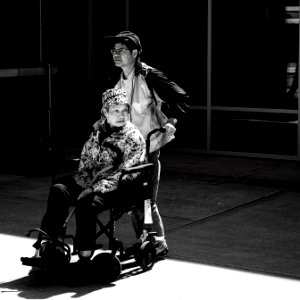 gray scale photo of man pushing wheelchair