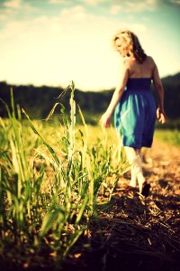 selective focus photo of woman wearing blue dress standing on grass field photo