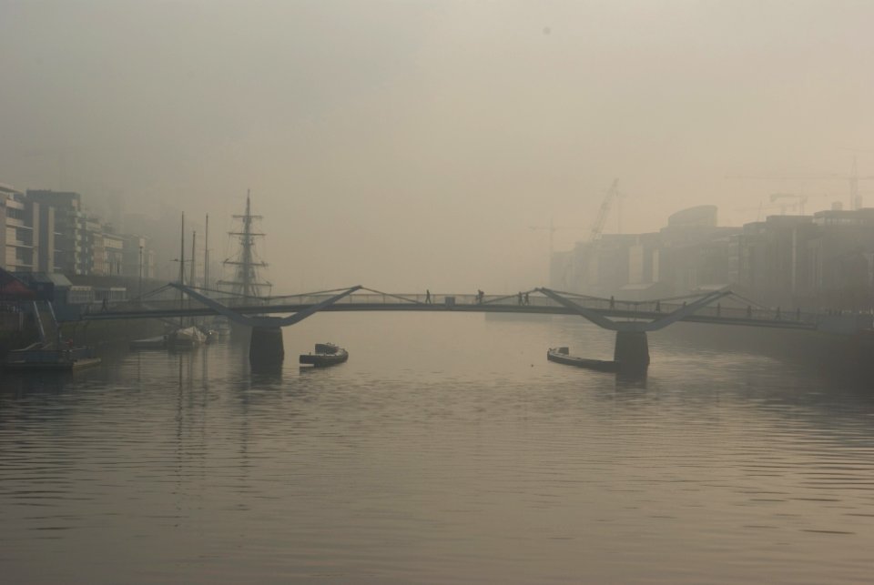 two boats below bridge with fogs