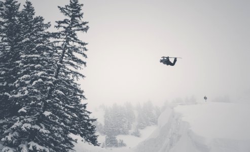 man jump on snow mountain using ski blades photo