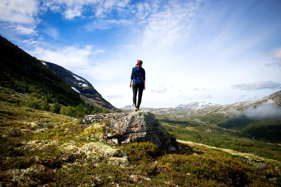 person standing on rock looking at mountain photo