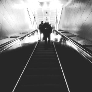 grayscale photography of man on escalator