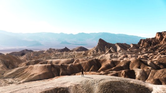 person standing on top of brown hill photo