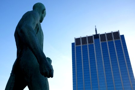 naked man statue in front high-rise building