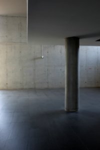 The inside of a building made of concrete walls with a platform supported by pillars. photo