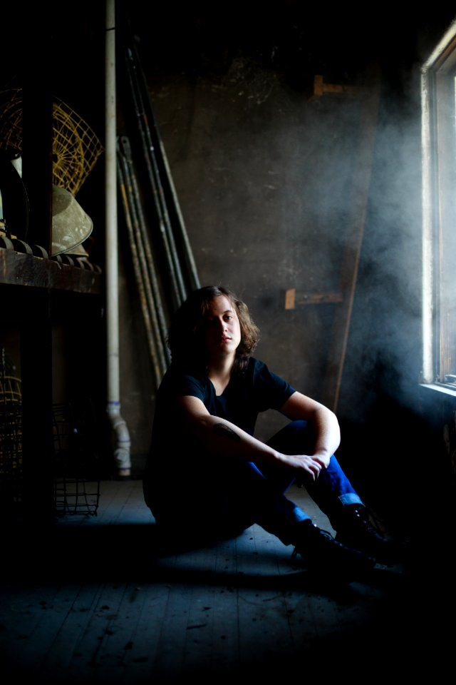 man sitting while resting his arms on his knee inside concrete building photo