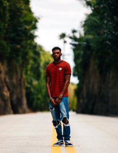 man in red shirt and blue distress denim jeans standing in middle of road photo