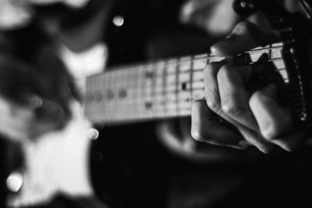 grayscale photo of person playing guitar photo