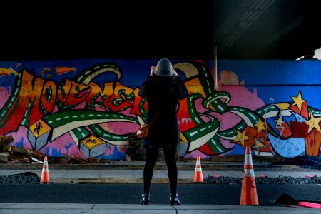 woman in blue coat standing in front of wall graffiti photo