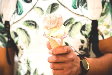 person holding ice cream cone with three flavors of ice cream