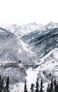 black bridge surrounded by mountain covered with snow under white sky photo
