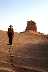 man wearing hat walking on desert