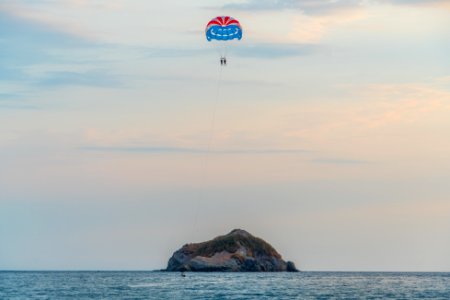 two people paragliding towards islet photo