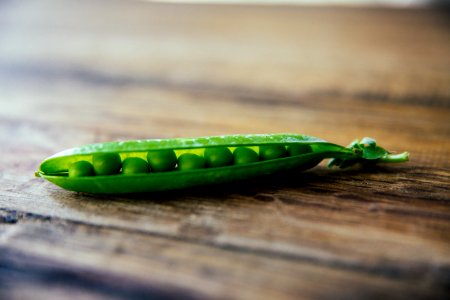 shallow focus photography of green pea on brown wooden surface photo