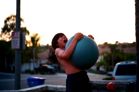 boy's hugging yoga ball while opening mouth photo