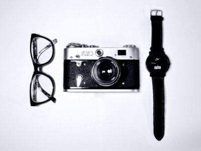 black and silver camera; eyeglasses with black frames; black analog watch photo
