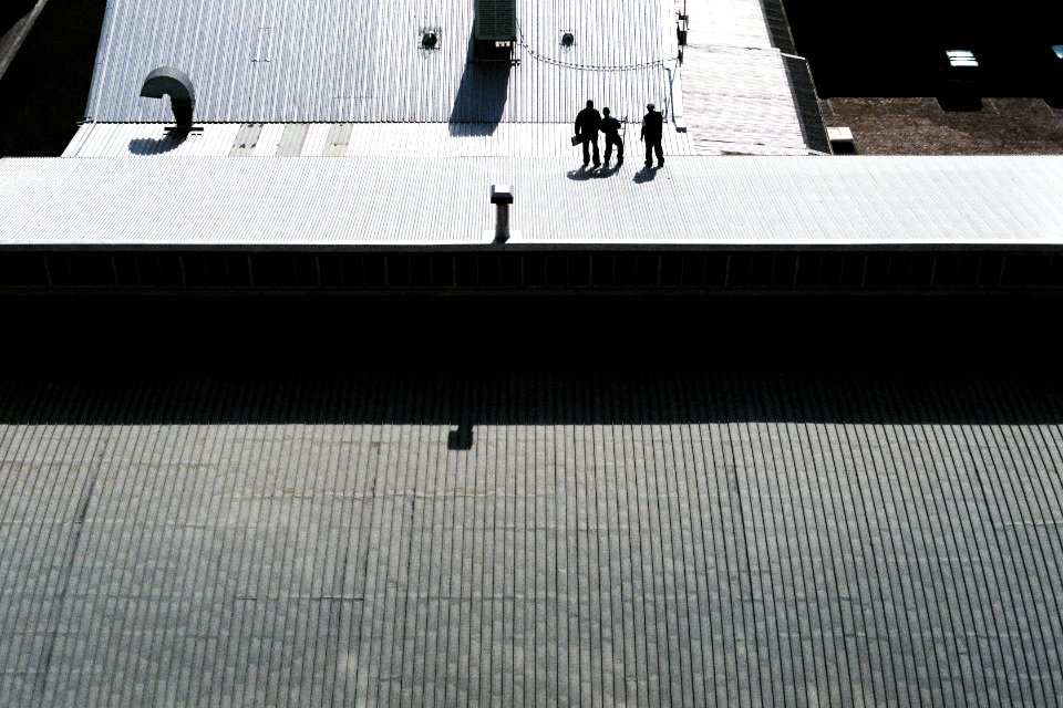 three men standing on gray pavement