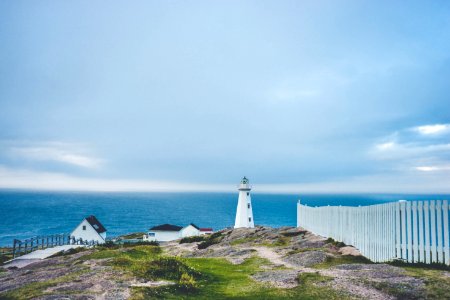 lighthouse on cliff near fence and house