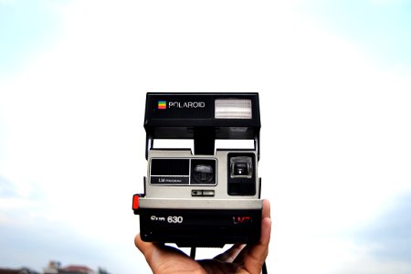 person holding black and gray Polaroid 630 instant camera