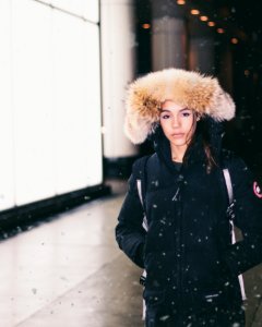 woman in black parka jacket standing while snowing photo