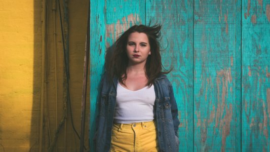 woman in white top leaning on wall photo