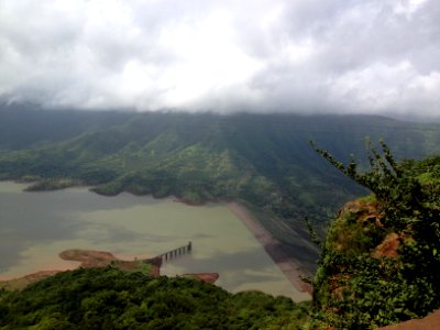 body of water surrounded by trees under cloudy skies