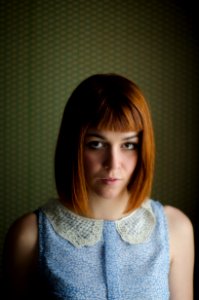 woman in blue floral sleeveless top in front of a wall photo