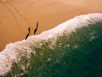 aerial photography of two person walking on shore photo