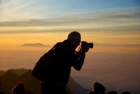 man using DSLR camera on mountain photo