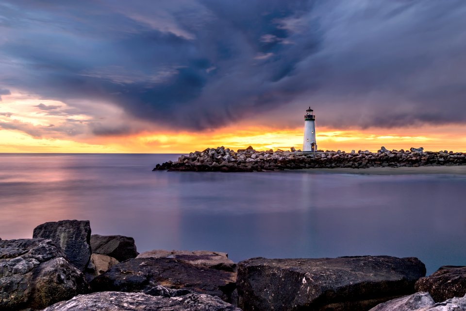 white lighthouse on shore beside body of water