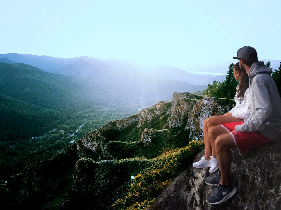 couple sitting on edge while looking at the mountains photo