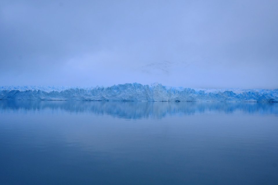 photography of sea near mountain covered with snow