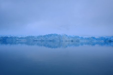 photography of sea near mountain covered with snow