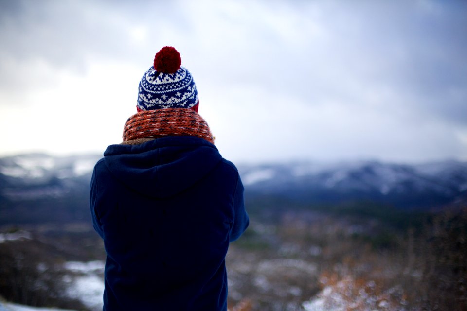 person wearing blue hoodie facing mountains