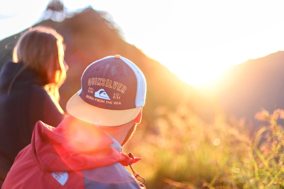 shallow photography of of man and woman sitting looking at sun rise