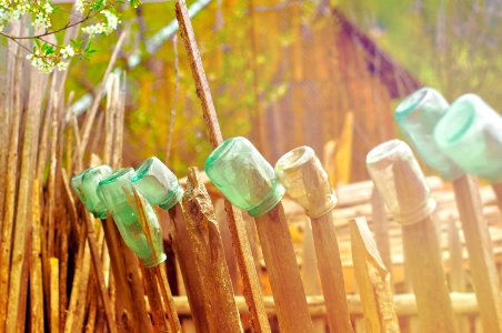 green glass jars on brown wooden fence photo